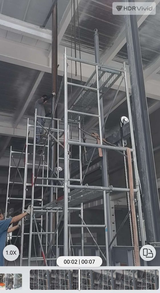 worker install guide rail hydraulic cargo lift warehouse